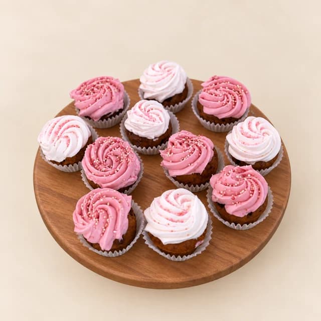 Classic cookie cake bites topped with pink buttercream swirls on a wooden board