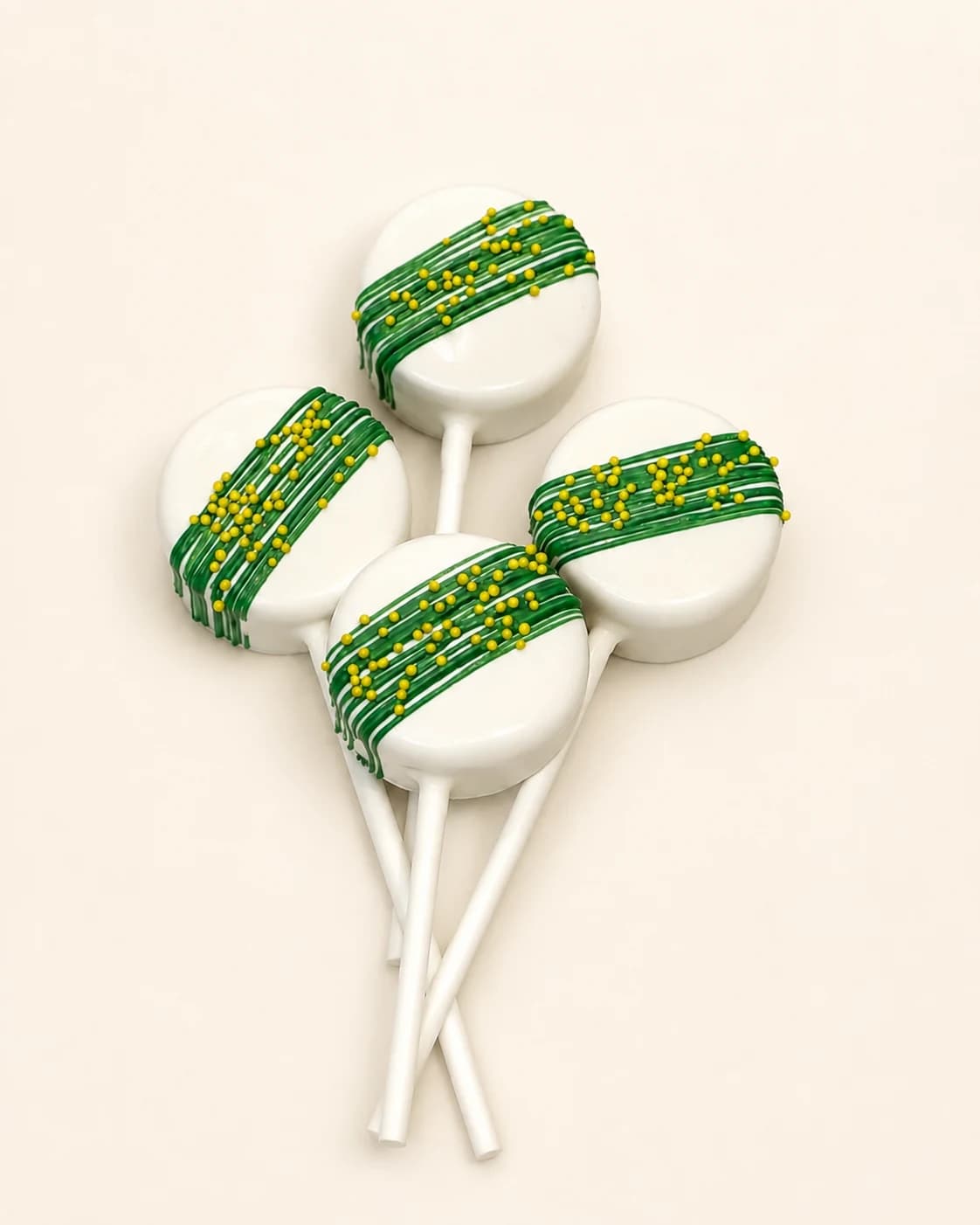 Classic cake pops with green diagonal drizzle and yellow sprinkles