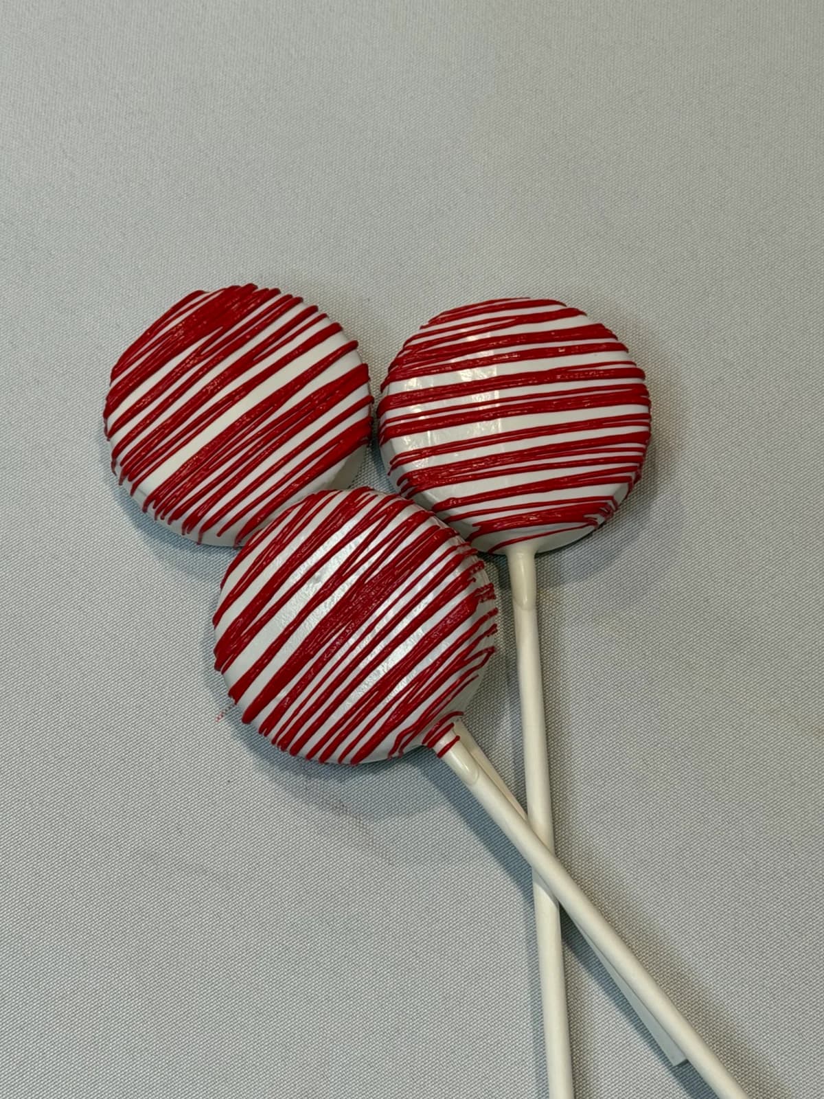 Classic cake pops dipped in white chocolate with red horizontal drizzle stripes