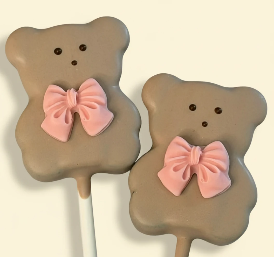 Teddy bear shaped cake pops with pink bow accents.